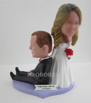 Humorous wedding cake topper bobbleheads bride pulling groom